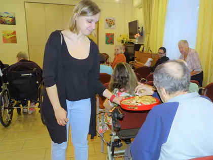 Prowadząca podaje ciastka mieszkańcom w świetlicy