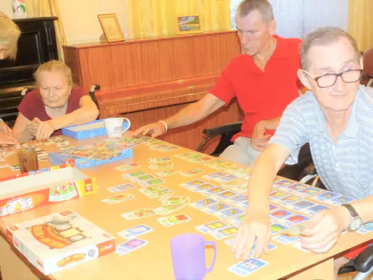 Mieszkańcy grają w grę edukacyjną z kartami przy dużym stole