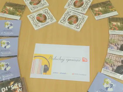 Płyty z audiobookami i ulotka Posłuchaj opowieści na stole