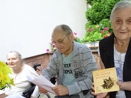Seniorzy uczestniczący w spotkaniu poetyckim w ogrodzie sensorycznym