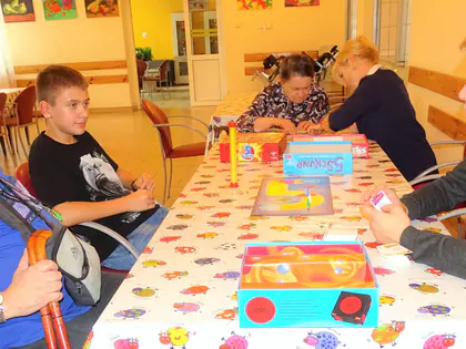 Mieszkaniec w niebieskiej koszulce gra z młodzieżą w gry przy stole