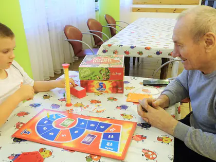 Chłopiec i mieszkaniec grają w grę planszową przy stole