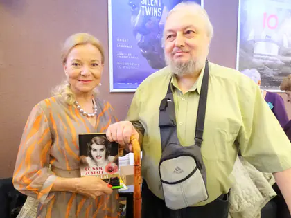 Aktorka Laura Łącz trzyma swoją książkę obok mieszkańca o lasce