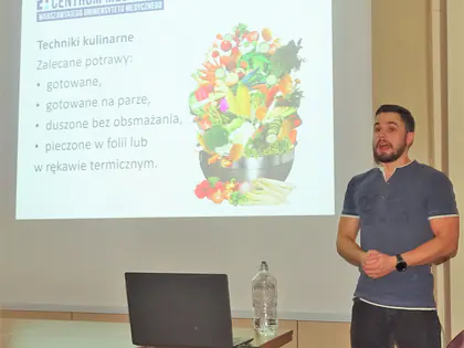 Prelegent z Centrum Medycznego mówi przy ekranie z prezentacją o zalecanych technikach kulinarnych