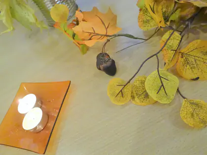 Tealight na tacy i jesienne liście na stole