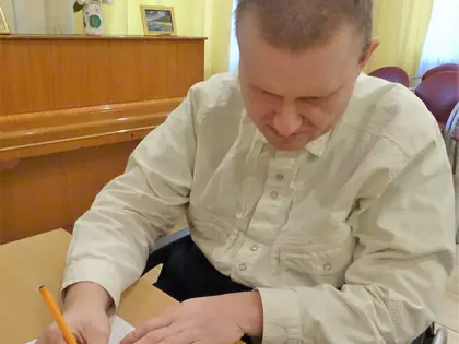 Mieszkaniec pisze list ołówkiem przy stole