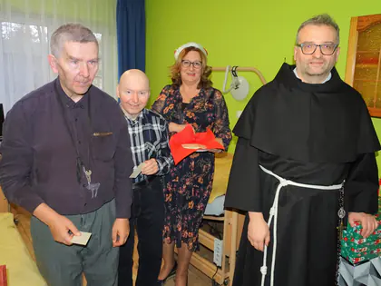 Dwaj mieszkańcy, pracownica w opasce Mikołaja i zakonnik w pokoju