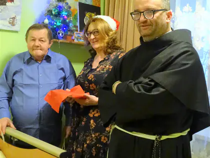 Mieszkaniec, kobieta w czapce Mikołaja i zakonnik w pokoju z choinką