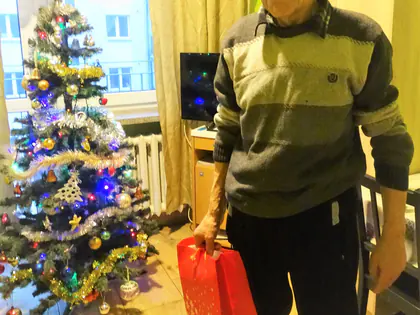 Mieszkaniec z czerwoną torbą przy choince w pokoju