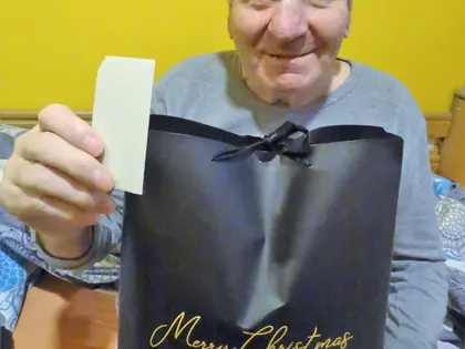 Uśmiechnięty mieszkaniec trzyma świąteczną torbę z napisem Merry Christmas