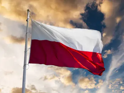 Biało-czerwona flaga Polski na maszcie na tle chmur