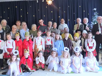 Przedszkolaki w strojach jasełkowych, aniołki i królowie, pozują z mieszkańcami i opiekunkami