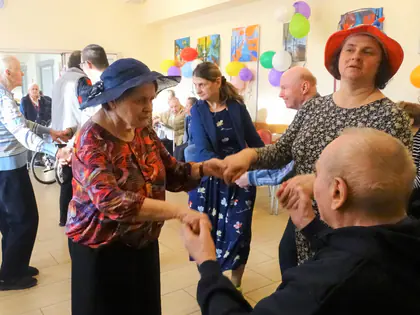 Mieszkanki w kapeluszach tańczą z mieszkańcami podczas zabawy