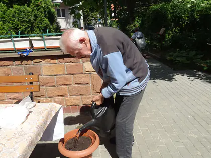 Mieszkaniec podlewa doniczkę konewką w ogrodzie