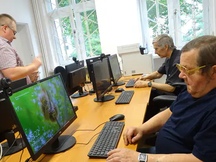 Seniorzy pracują przy komputerach w pracowni