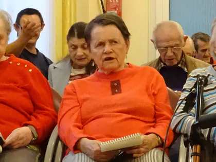 Mieszkanki z notesami ze śpiewnikami śpiewają w sali