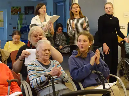 Młodzież śpiewa i klaszcze z mieszkańcami w świetlicy