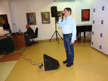 Piosenkarz śpiewa do mikrofonu w galerii z obrazami