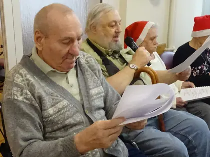 Mieszkańcy w czapkach Mikołaja czytają teksty przy stole