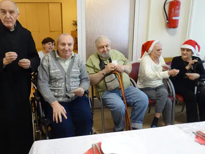 Ksiądz składa życzenia mieszkańcom w czapkach Mikołaja