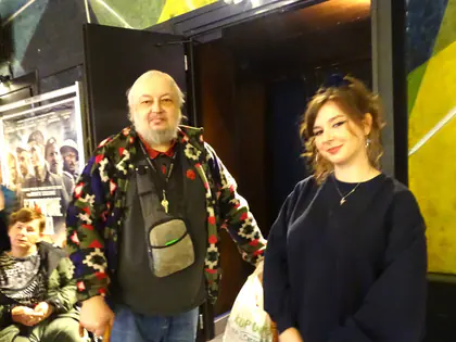Mężczyzna w kolorowej kurtce i młoda kobieta stoją w holu kina