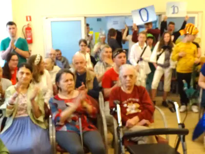 Mieszkańcy i młodzież w kostiumach, jedna osoba w stroju syreny, w tle uczestnicy z planszami