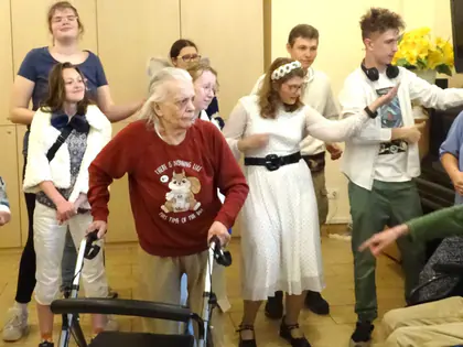 Młodzież i mieszkańcy w kostiumach występują razem w sali