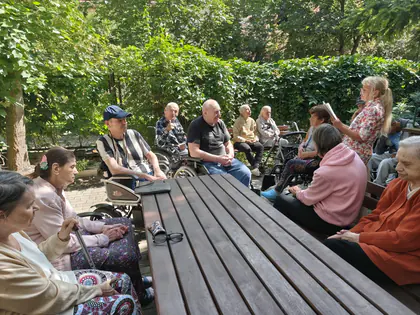 Mieszkańcy czytają przy stole w ogrodzie