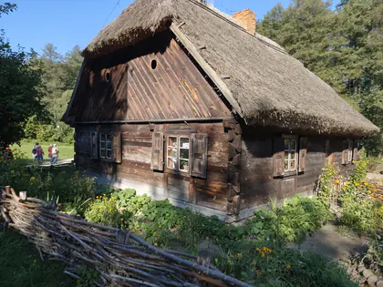 Drewniana chata kryta strzechą z ogródkiem