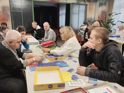 Mieszkańcy i młodzież grają w karty przy stole