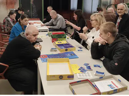 Mieszkańcy i młodzież przy stołach z grami