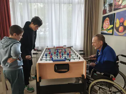 Chłopcy grają w piłkarzyki z mieszkańcem na wózku