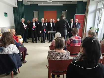 Mieszkańcy słuchają koncertu chóru męskiego