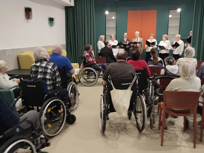 Mieszkańcy na wózkach słuchają występu zespołu