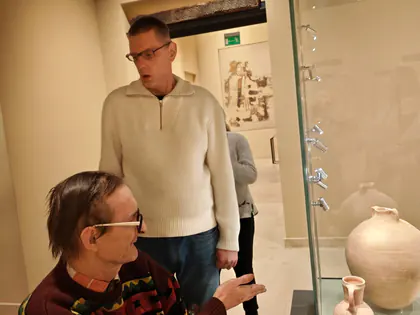 Mieszkańcy przy gablocie z glinianymi naczyniami w muzeum