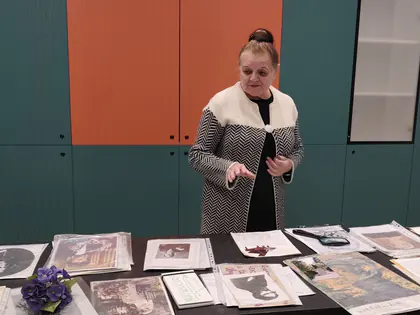 Przewodniczka opowiada o Fryderyku Chopinie przy stole z fotografiami i fiołkami