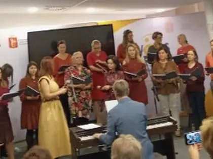Chór uczniów śpiewa w sali z pianinem