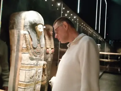 Mężczyzna ogląda drewniany sarkofag egipski w oświetlonej gablocie