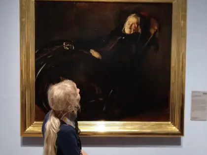 Mieszkanka ogląda portret w złotej ramie w muzeum