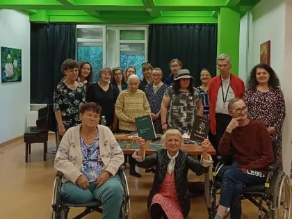 Grupa mieszkańców i gości pozuje z książkami w sali