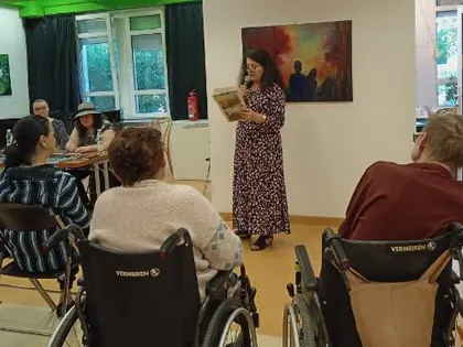 Prowadząca czyta mieszkańcom w świetlicy