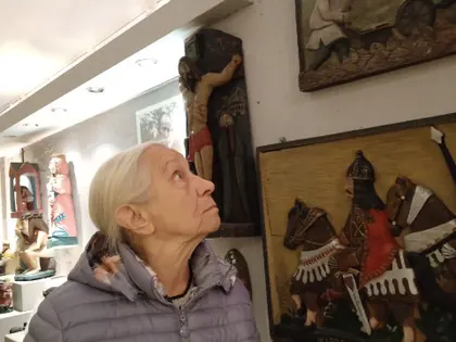 Starsza kobieta ogląda rzeźby i drewniane obrazy na ścianie muzeum