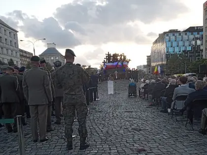 Uroczystość na brukowanym placu, na pierwszym planie żołnierze, w głębi zgromadzeni uczestnicy