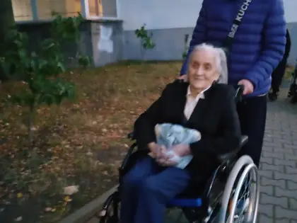 Chłopak pcha wózek z mieszkanką w czarnym płaszczu