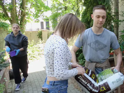 Uczniowie z workiem ziemi do kwiatów w alejce ogrodu