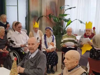 Mieszkańcy w papierowych koronach czytają kolędy