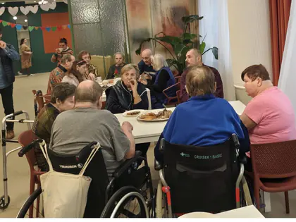 Mieszkańcy przy stołach w świetlicy podczas poczęstunku