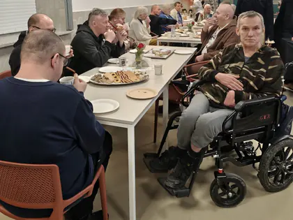 Mieszkańcy przy stołach z ciastkami, jeden na wózku