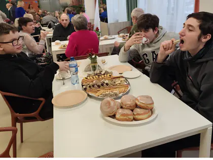 Chłopcy i mieszkańcy jedzą pączki przy stole