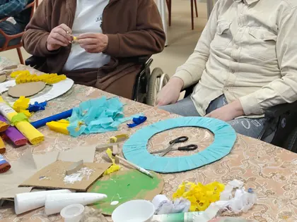 Mieszkańcy przy stole pełnym materiałów plastycznych